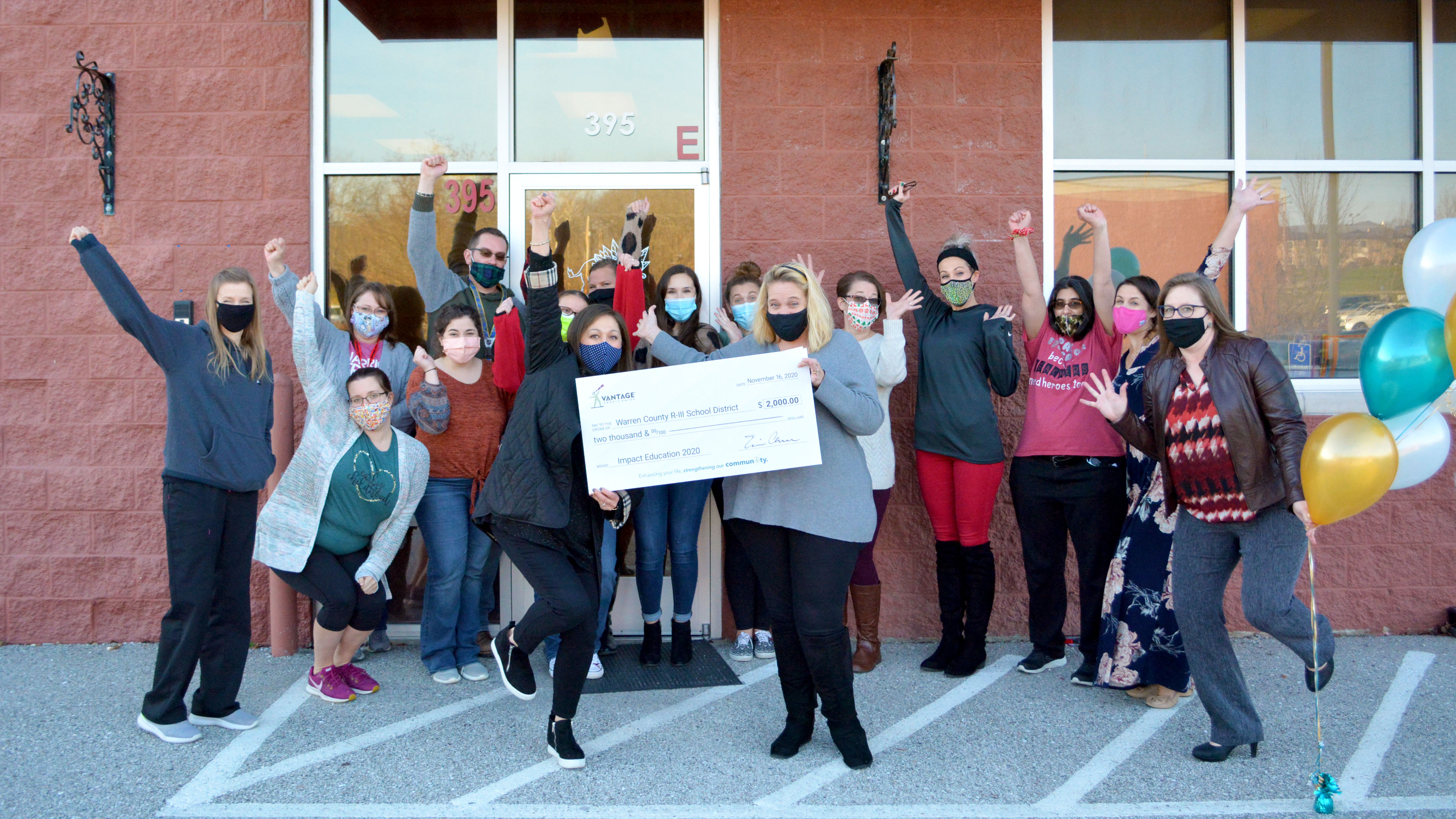 Teachers holding a large check