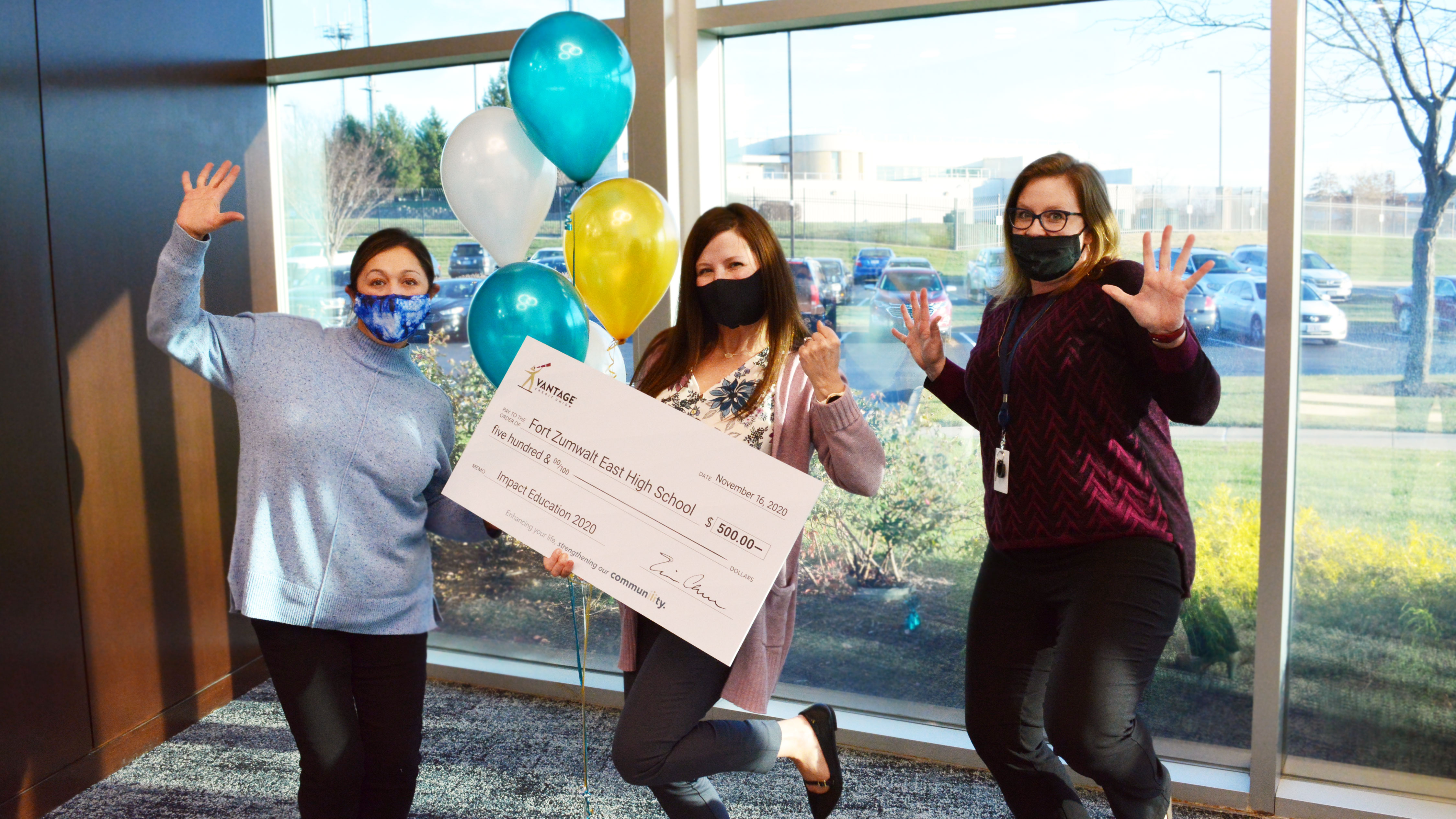 Three teachers holding a large check