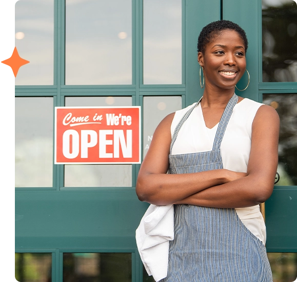 Woman business owner standing next to open door sign