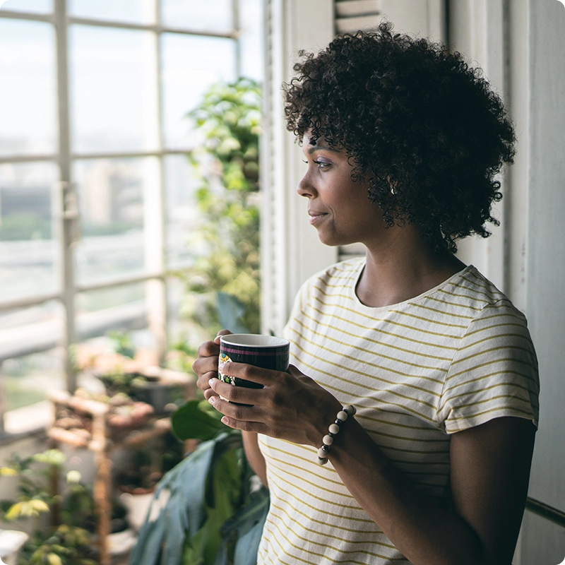 Woman with morning coffee looking out window