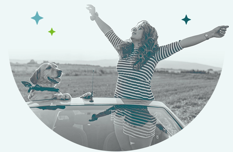 A woman in a convertible standing with her arms out